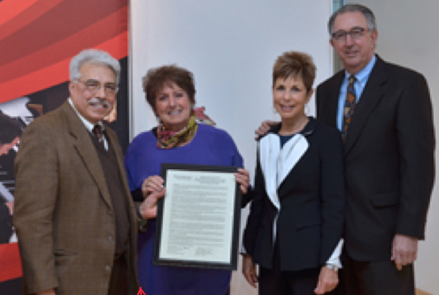 Photo of alumni holding a framed document