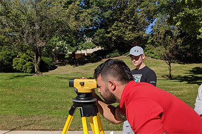 student using surveying tool outdoors